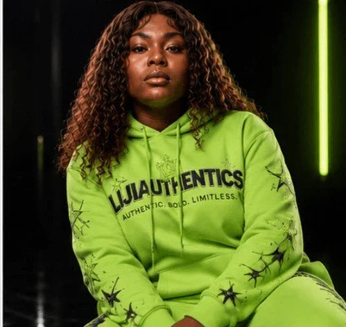 Woman in neon green LIJIAUTHENTICS hoodie with star graphics, bold streetwear style
