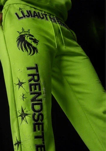 Neon green sweatpants with lion crown graphic, 'TRENDSETTER' text, and star prints — bold streetwear style