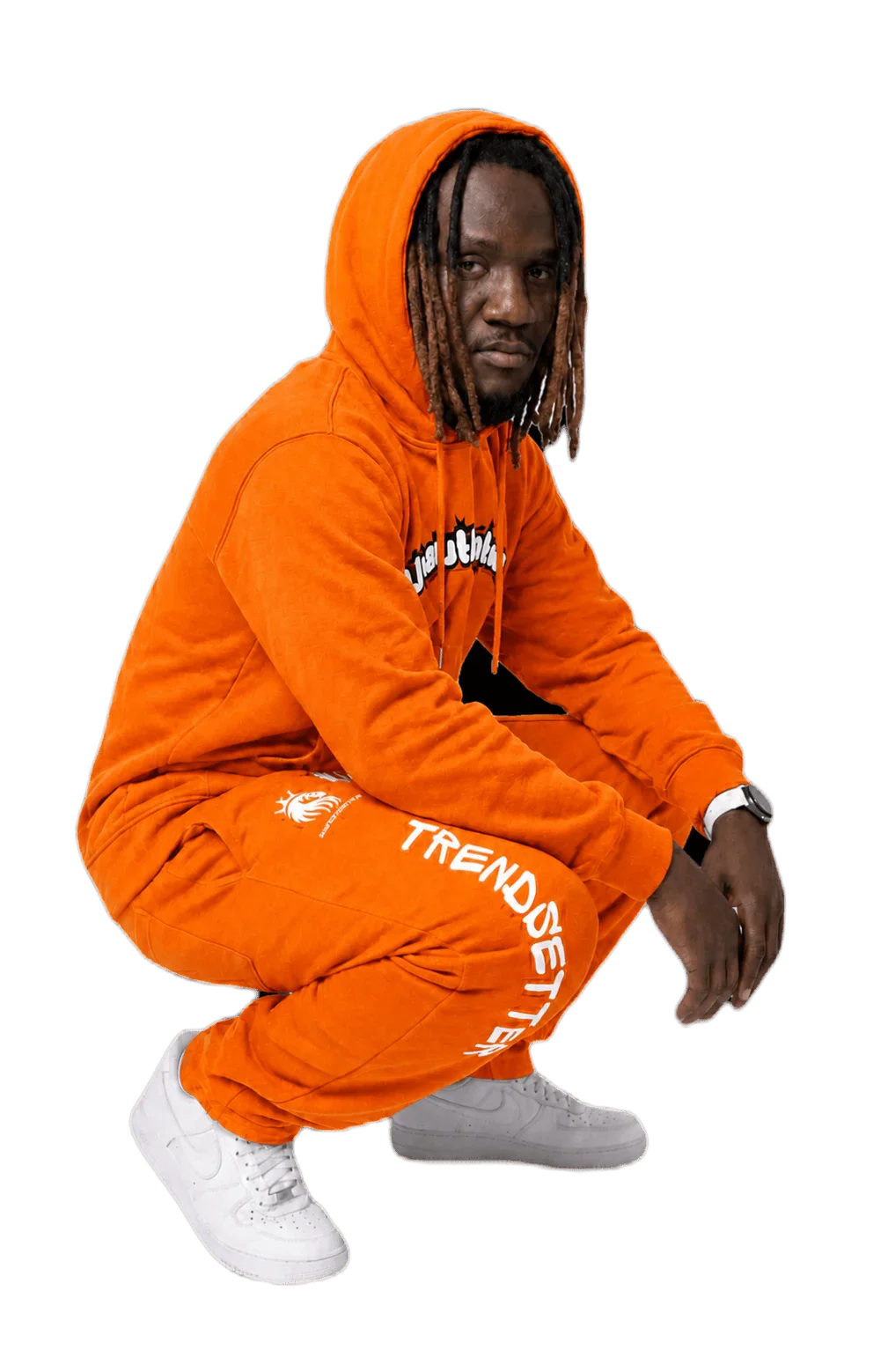 Man in bold orange matching sweatsuit with 'TRENDSETTER' print, crouching in streetwear style